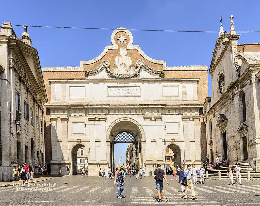 Porta del Popolo em Roma, uma grandiosa entrada situada na Piazza del Popolo. A estrutura atual, reformada por Bernini em 1655, destaca-se por sua arquitetura monumental, criada para receber a rainha Cristina da Suécia. A fachada é decorada com colunas e uma inscrição dedicada ao Papa Alexandre VII, além de elementos barrocos que conferem grandeza à entrada da cidade