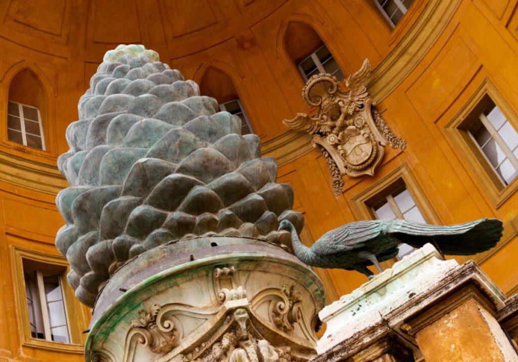 Escultura da "Pinha" de bronze localizada no Pátio da Pinha no Vaticano. A grande pinha é cercada por pavões, simbolizando eternidade e imortalidade. Uma peça de destaque da arte romana antiga, que combina beleza e significado espiritual.