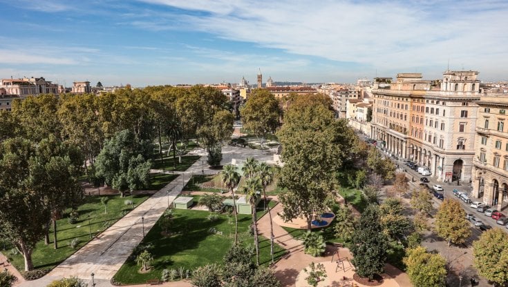 A imagem mostra a Piazza Vittorio Emanuele II no bairro Esquilino, em Roma. Este espaço verde amplo é rodeado por edifícios históricos e é um popular ponto de encontro. Com seus caminhos bem cuidados e áreas arborizadas, a praça oferece um refúgio tranquilo no coração da cidade.