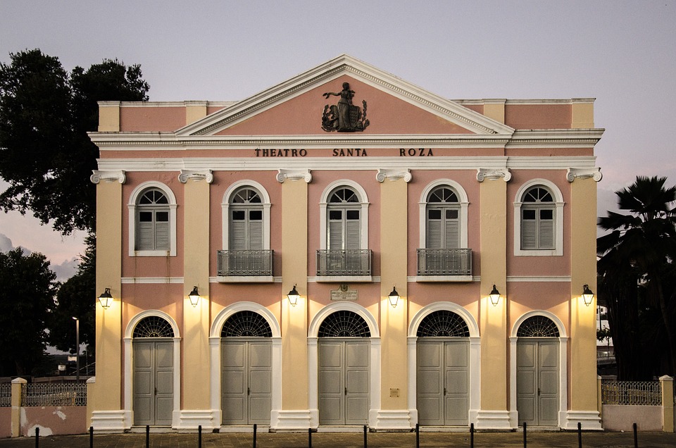 A imagem mostra a fachada do Theatro Santa Roza, em João Pessoa, com sua arquitetura italiana preservada. A estrutura destaca elementos como colunas simétricas e arcos, além do frontão triangular no topo, que mantém o charme histórico do teatro, inaugurado em 1889.