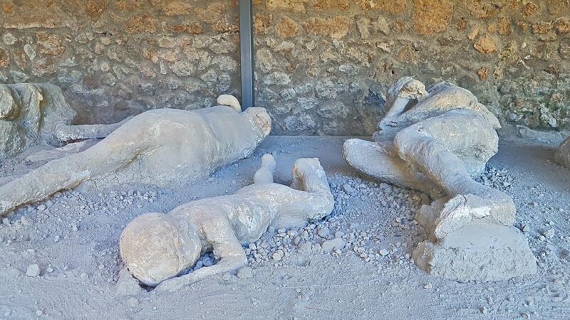 Reproduções em gesso de vítimas da erupção do Vesúvio, encontradas em Pompeia, capturando suas poses finais no momento do desastre.