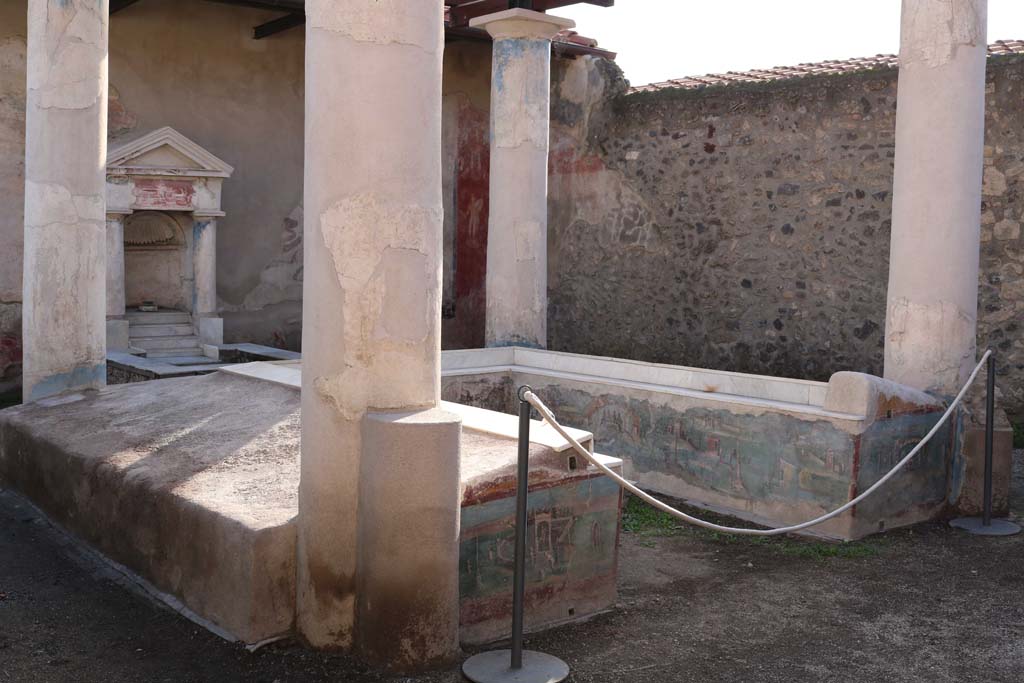 Restos de uma estrutura romana em Pompeia, com colunas coríntias e um afresco parcialmente preservado nas paredes, exibindo detalhes arquitetônicos e artísticos da Antiguidade.